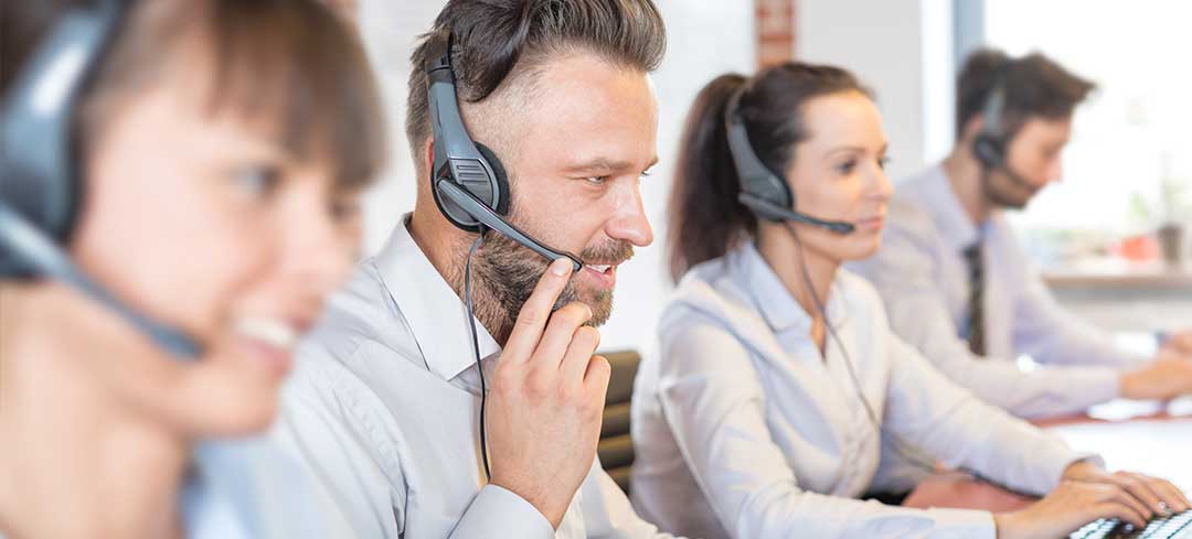 Vier Personen mit Headsets bei der Arbeit in einem Call Center.