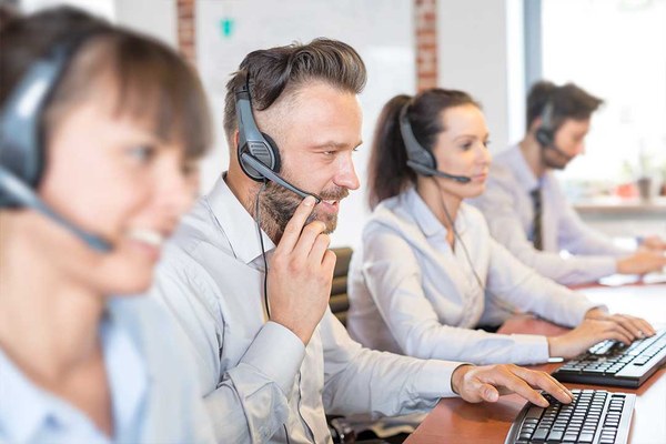 Vier Personen mit Headsets bei der Arbeit in einem Call Center.