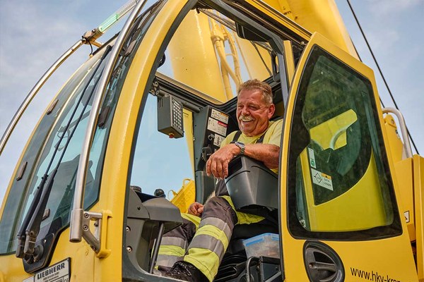Ein lächelnder Mann sitzt in der Kabine eines Autokrans.