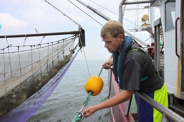 Fischer zieht ein Fischernetz an Bord