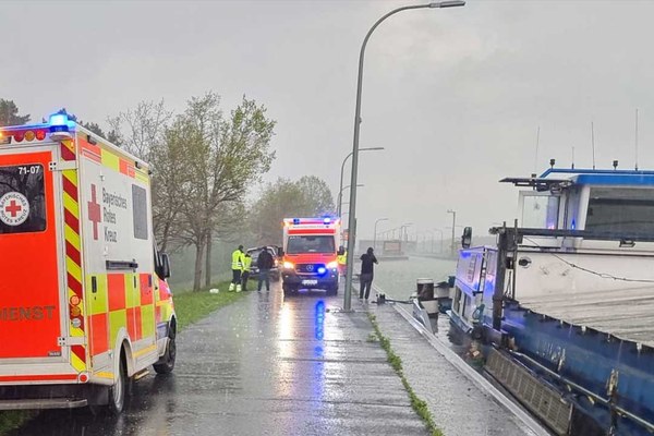 Rettungswagen steht bei Regenwetter an einer Kanalschleuse