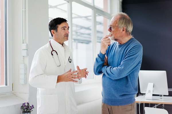 Ein Arzt berät einen Patienten. Beide stehen sich gegenüber