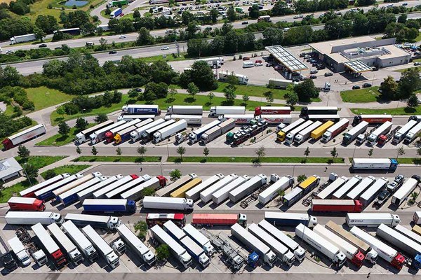 Luftaufnahme eines überfüllten Lkw-Rastplatzes an einer Autobahn