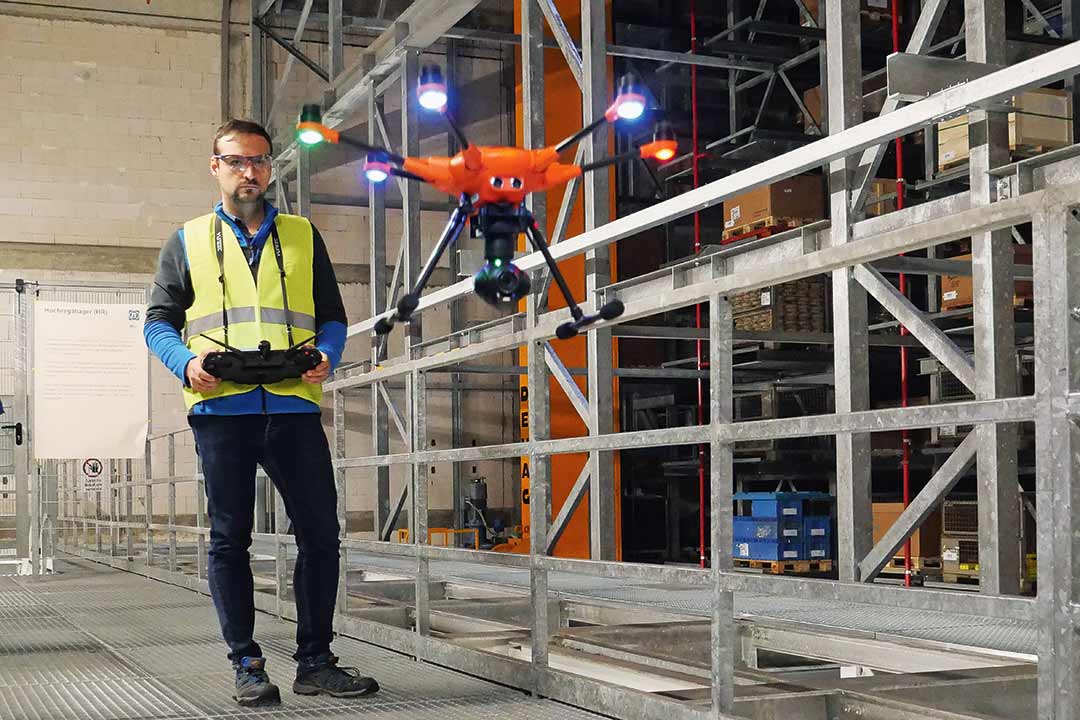 Multikopter oder Drohnen im Arbeitseinsatz Mitarbeiter im Lager fliegt einen Multikopter an einem Regal entlang