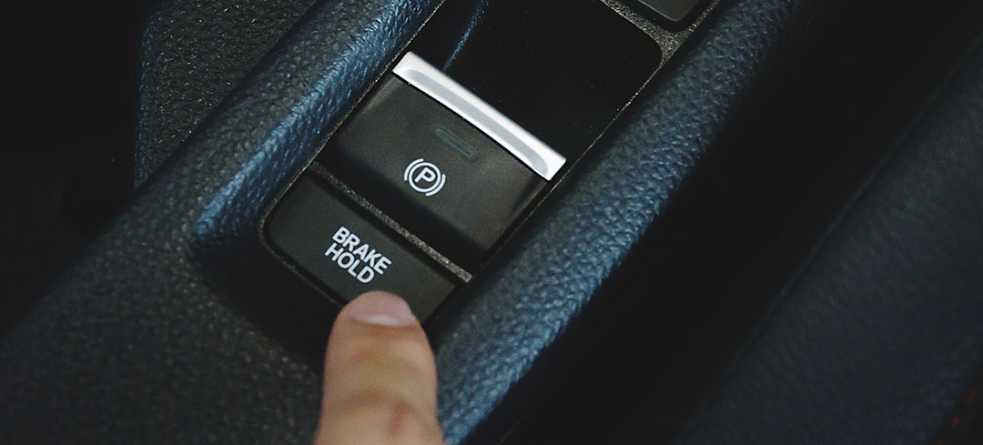 Automatische Feststellbremse kann Leben retten Finger drückt die elektronische Feststellbremse