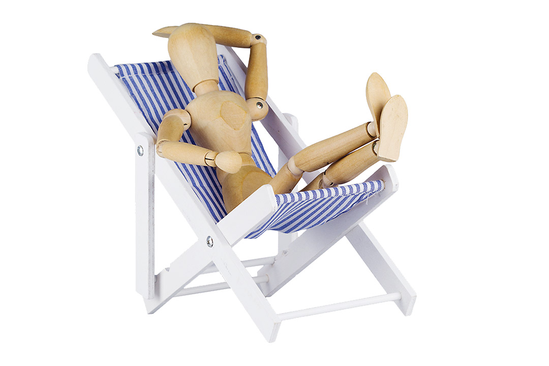 Holzpuppe ruht sich einem Liegestuhl aus