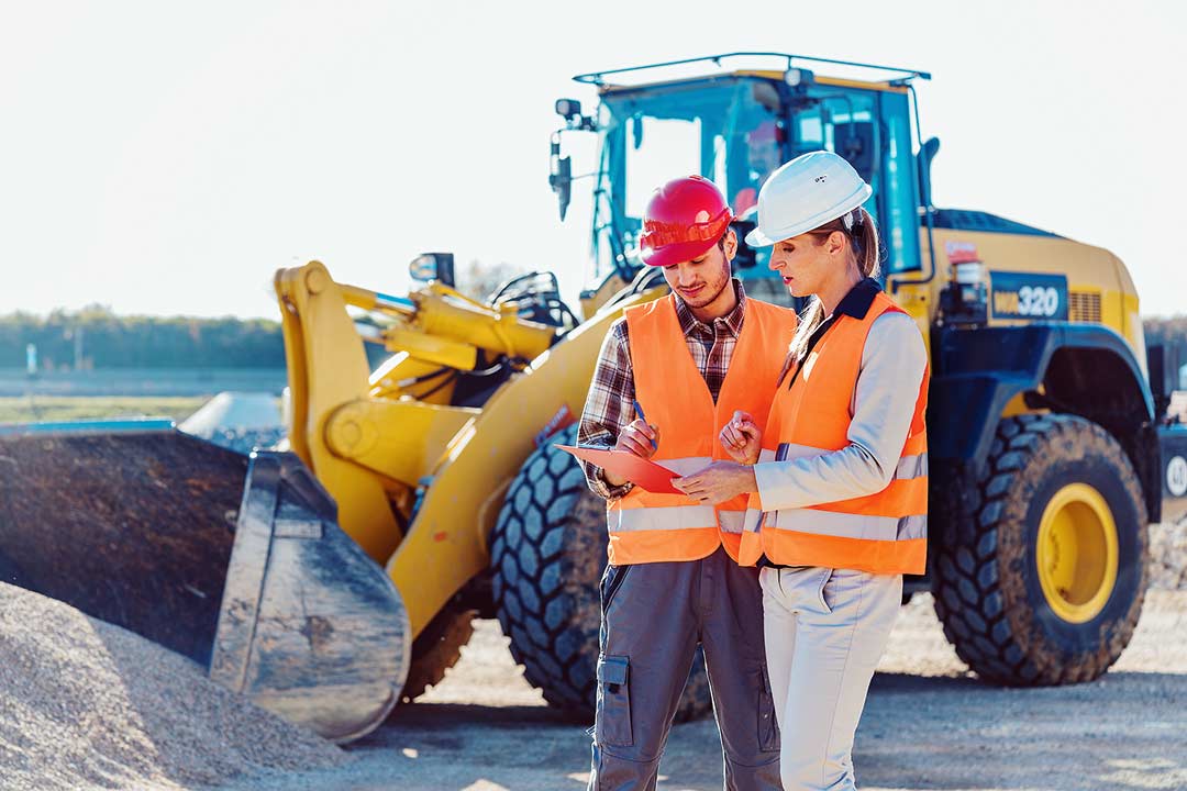 Mitarbeiter besprechen sich vor einem Radlader