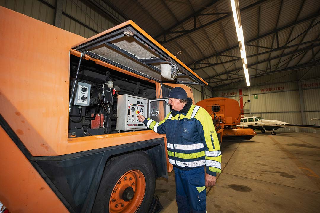 Heinz Krüger am Schalterkasten des Kehrblasgeräts. Am Kieler Flughafen befinen sich zwei der zwölf Meter langen Maschinen.