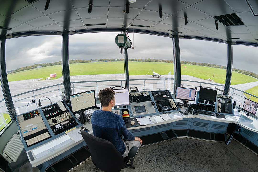 Mitarbeiter Dennis Schaller sitzt im Tower des Kieler Flughafens und beobachtet das Geschehen