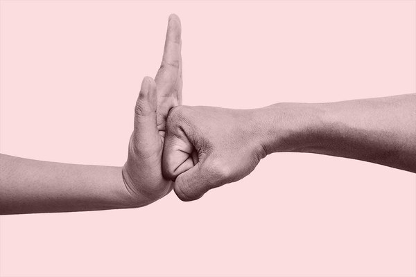 Eine flache Hand stoppt eine zur Faust geballte Hand.