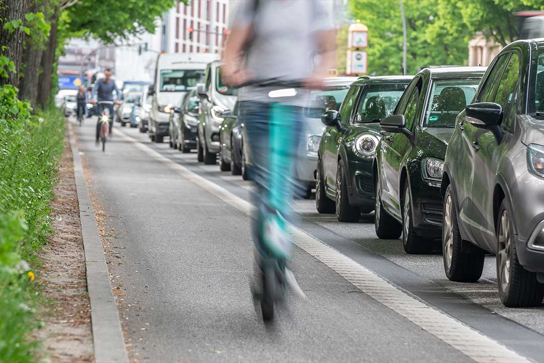 Ein Elektro-Roller fährt auf einem Fahrradweg an einem Stau vorbei. Ein Elektro-Roller fährt auf einem Fahrradweg an einem Stau vorbei.