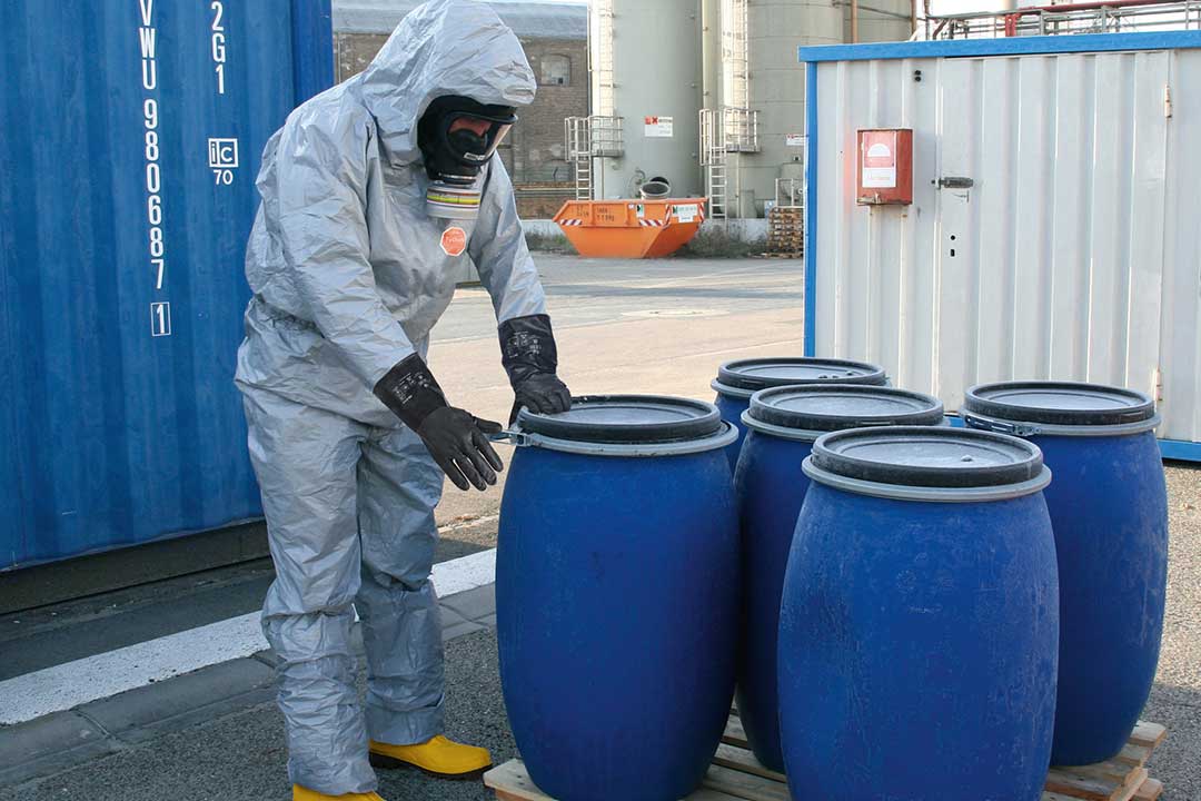 Mitarbeiter in Schutzkleidung bei der Entsorgung von chemischen Abfällen