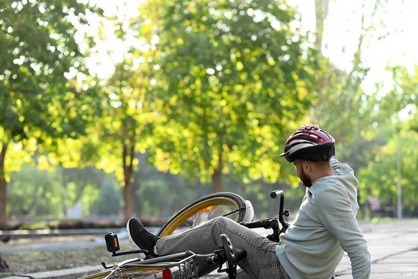 Ein Mann mit Fahrradhelm auf dem Kopfliegt neben einem umgestürzten Fahrrad.