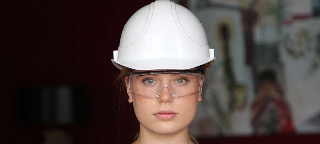 Beispiel für eine gute Schutzbrille. Eine Frau mit Schutzhelm und Schutzbrille schaut in die Kamera.