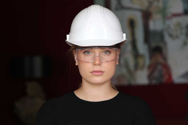 Eine Frau mit Schutzhelm und Schutzbrille schaut in die Kamera.