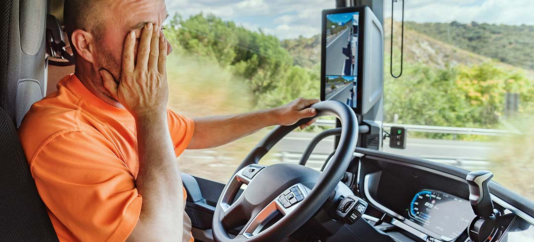 Kranker Lkw-Fahrer fasst sich beim Fahren an die Stirn