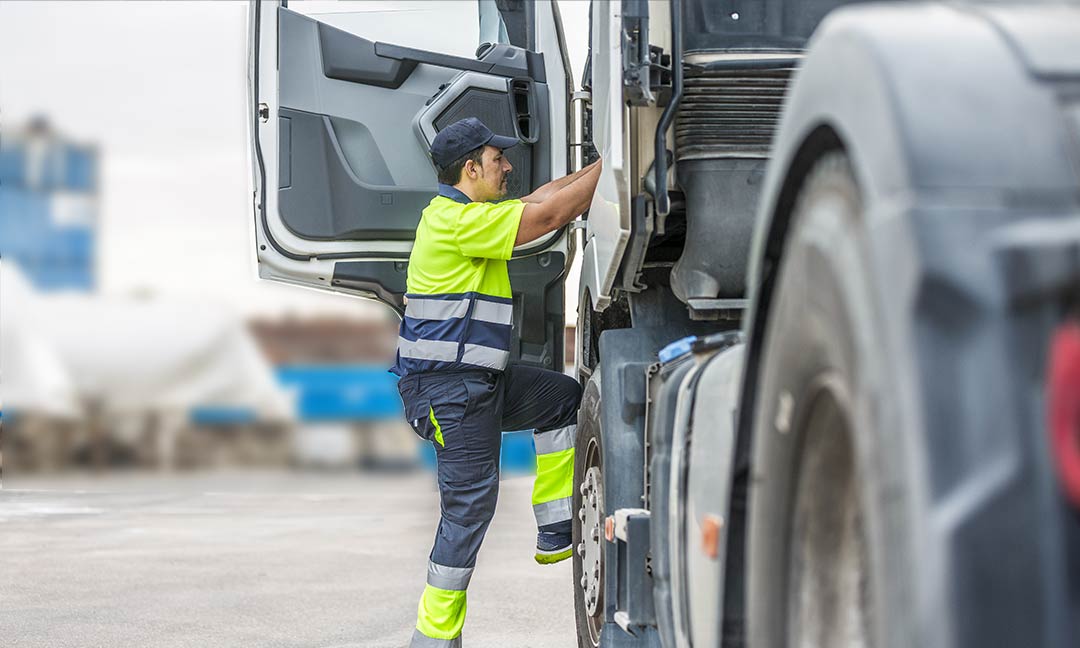Mann in Warnkleidung steigt in Lkw Fahrerhaus