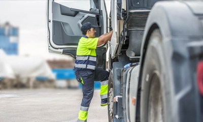 Mann in Warnkleidung steigt in Lkw Fahrerhaus