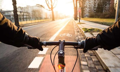Hände an Fahrradlenker auf einem Radweg