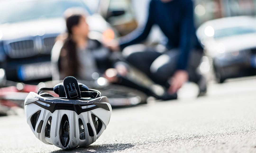 Fahrradhelm liegt auf Straße dahinter verschwommen eine auf der Straße liegende Person